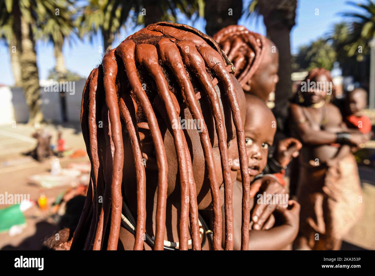 Femme Himba avec de la boue dans ses cheveux pour la protéger du soleil, portant un bébé. Banque D'Images