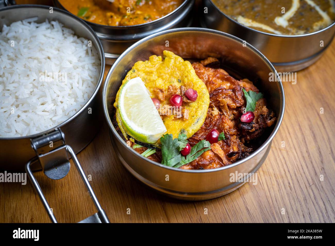 Un gros plan de boîtes de tiffins contenant divers currys dans un restaurant indien. Banque D'Images