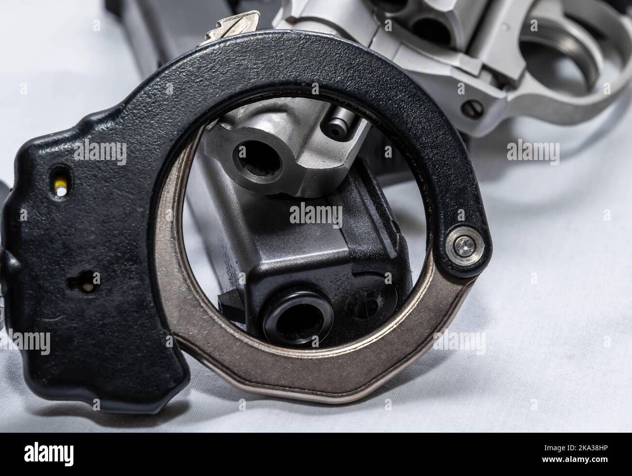 Deux pistolets, un pistolet noir 9mm et un magnum en acier inoxydable 357 avec la moitié d'un ensemble de menottes sur un fond blanc Banque D'Images