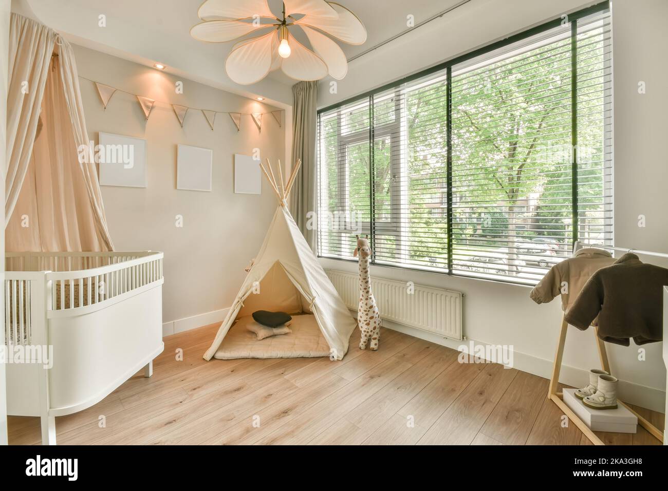 Intérieur d'une chambre avec un lit de bébé en bois à côté d'une fenêtre lumineuse et d'une tente Banque D'Images