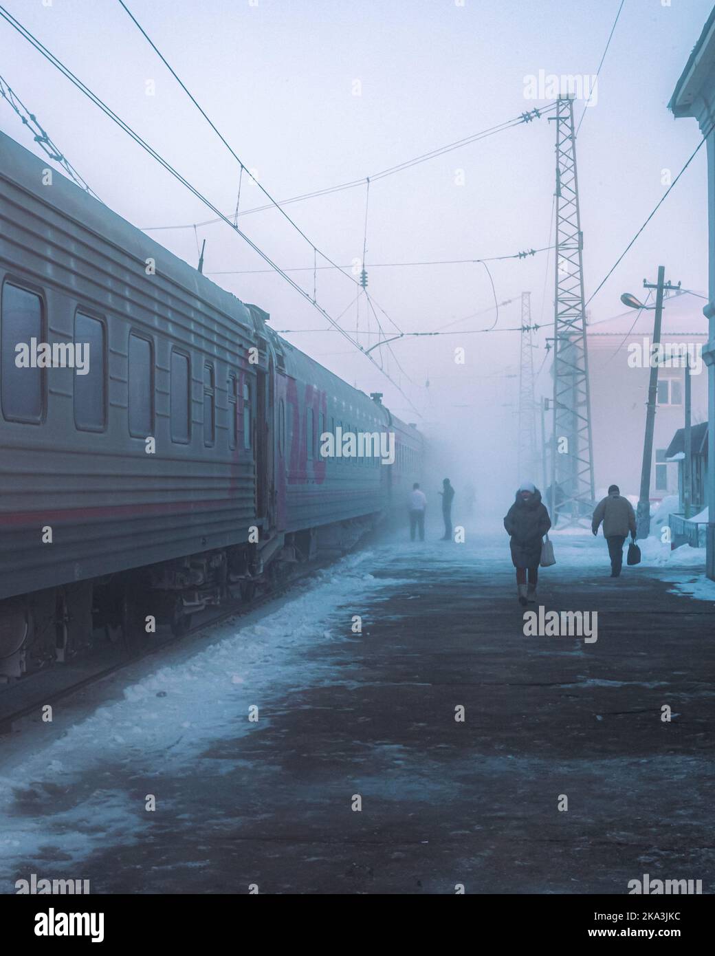 gare tôt le matin à l'heure d'hiver enneigée, personnes méconnaissables sur la plate-forme Banque D'Images