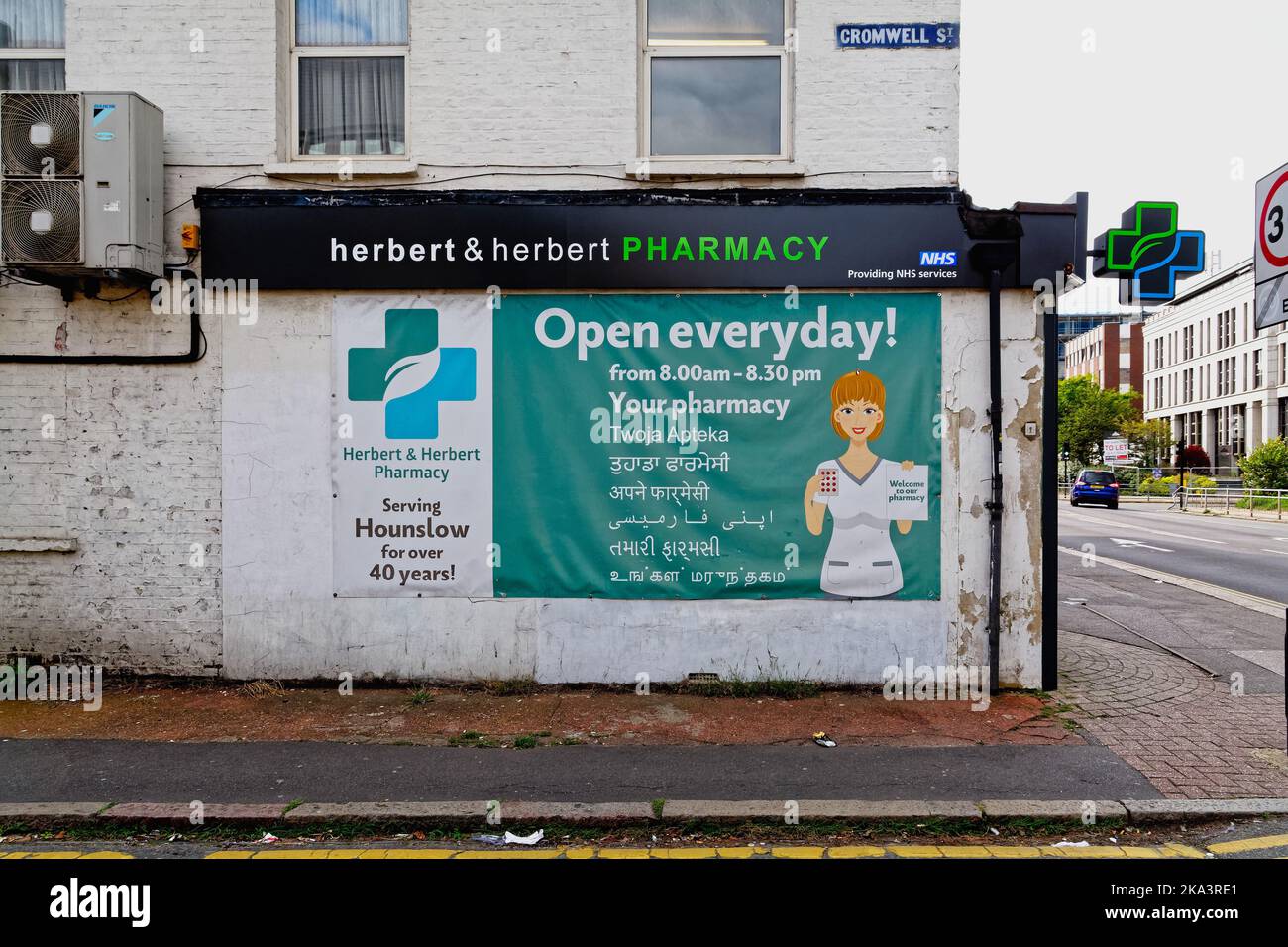Extérieur de la pharmacie Herbert et Herbert à Hounslow avec une grande affiche d'information en anglais polonais et hindi pour aider les communautés mixtes, Londres UK Banque D'Images