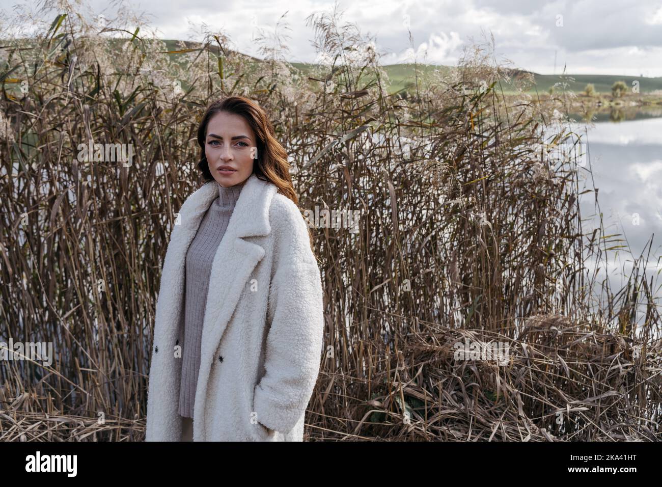 Portrait d'une belle femme portant un manteau d'hiver debout au bord d'une rivière, en Biélorussie Banque D'Images