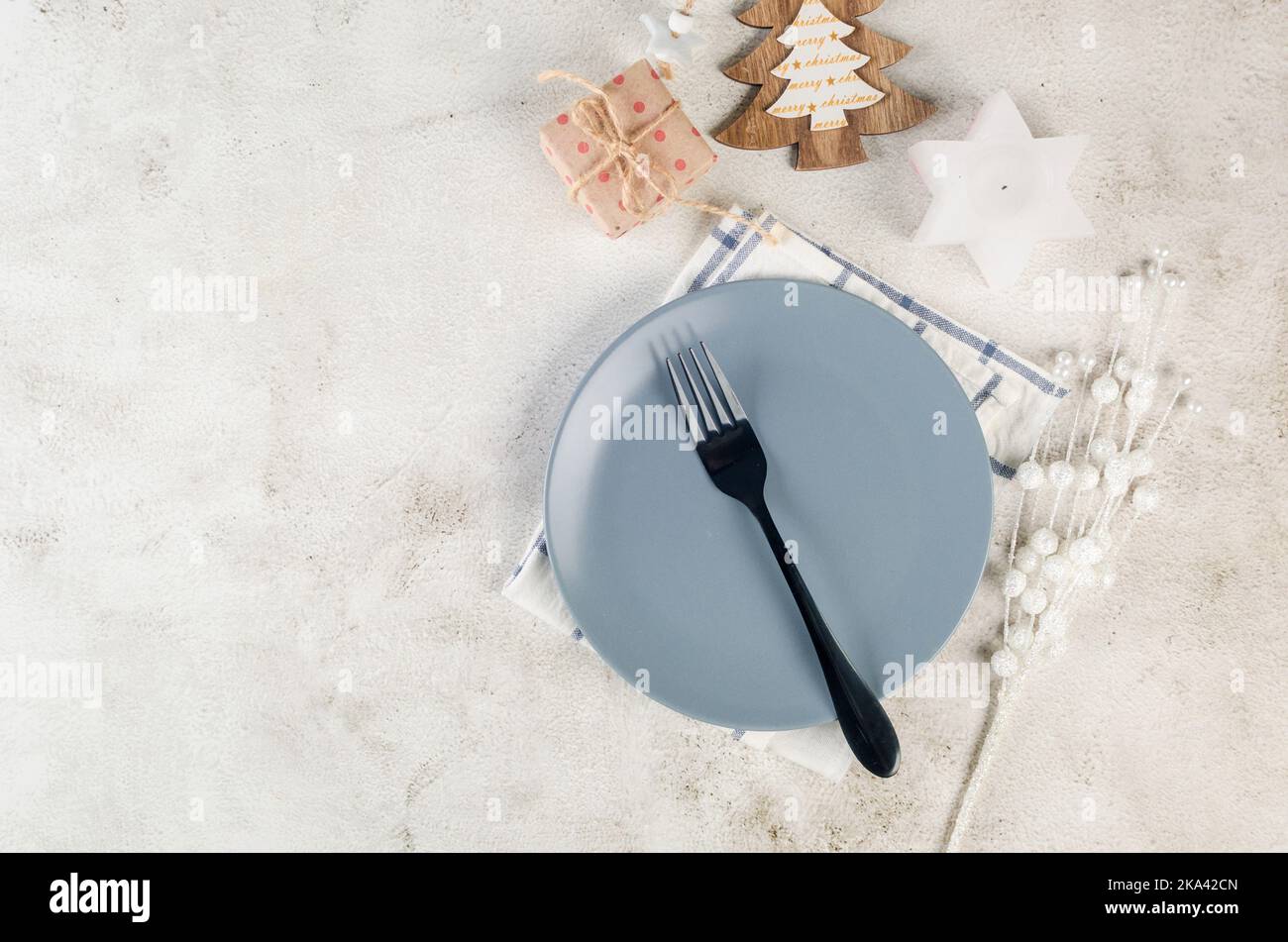 Table de Noël. Vue de dessus d'une assiette grise vide avec des couverts  noirs et des décorations artisanales en bois sur une table lumineuse.  Décoration de table d'événement Photo Stock - Alamy