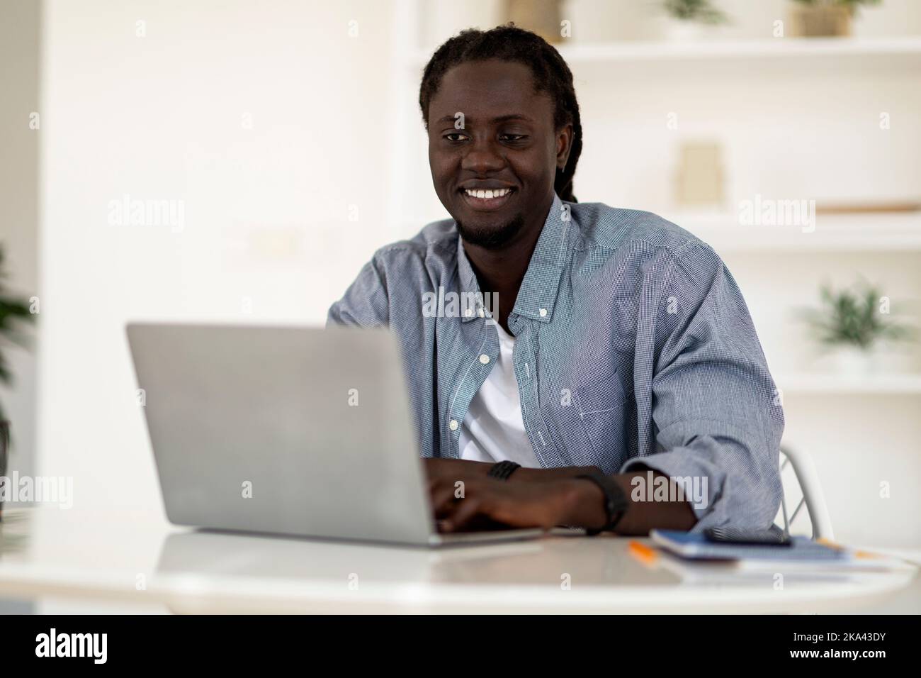 Carrière freelance. Portrait d'un jeune homme noir souriant travaillant avec un ordinateur portable Banque D'Images
