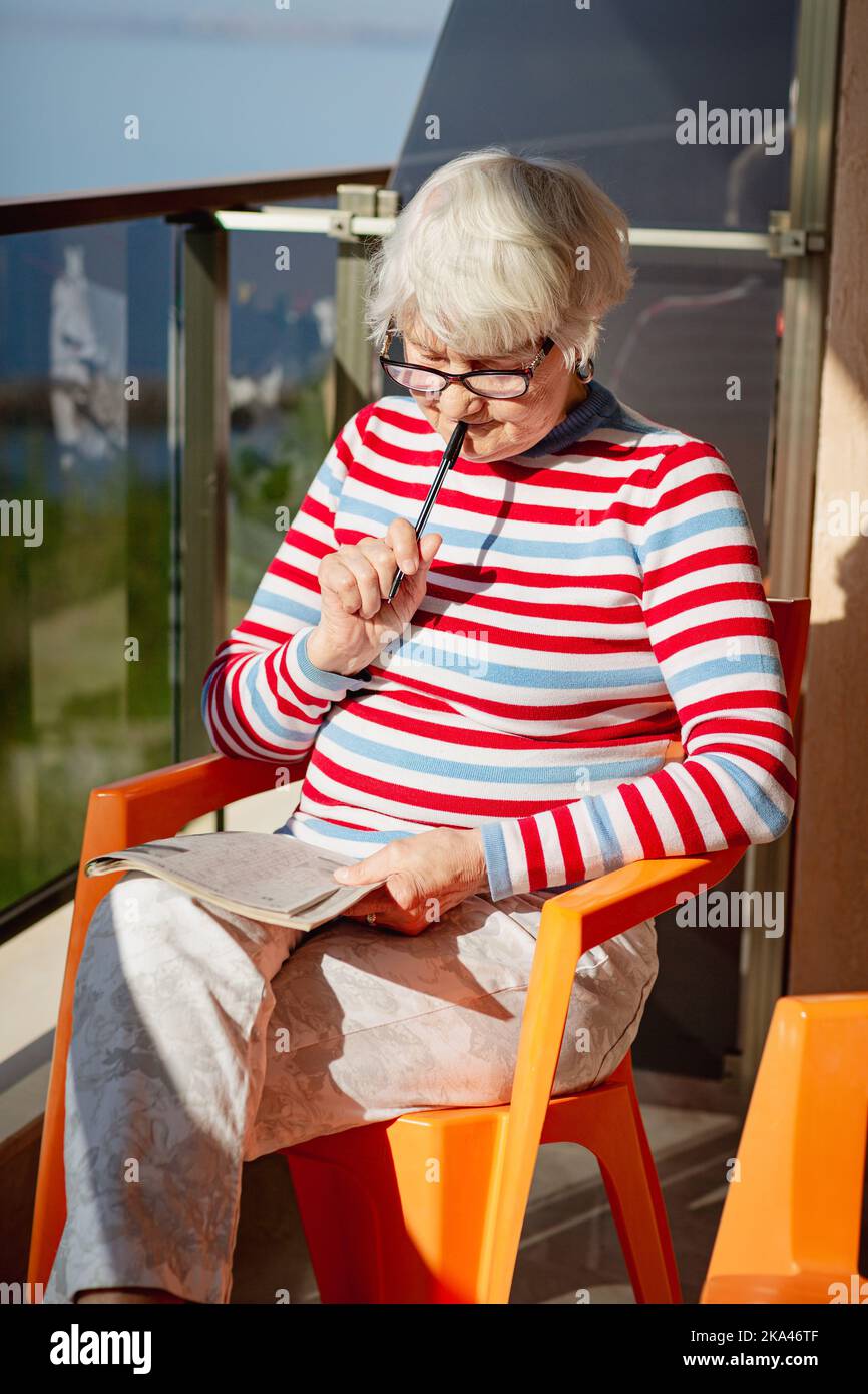 Femme âgée en lunettes, assise sur un balcon près de la mer Banque D'Images