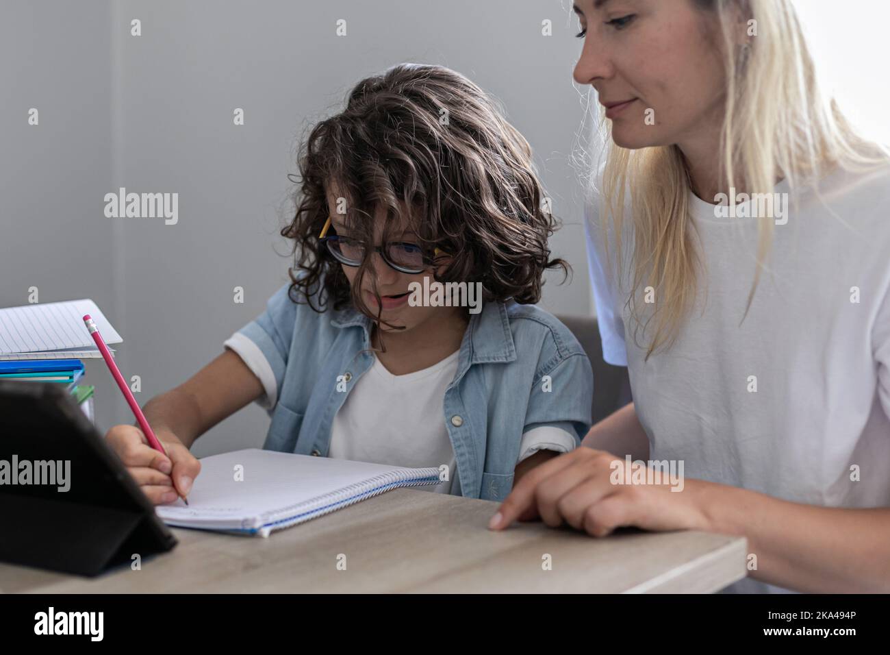 Lunettes de mère et de petit fils étudier en ligne sur tablette à la maison ensemble de la leçon, préparer les devoirs Banque D'Images
