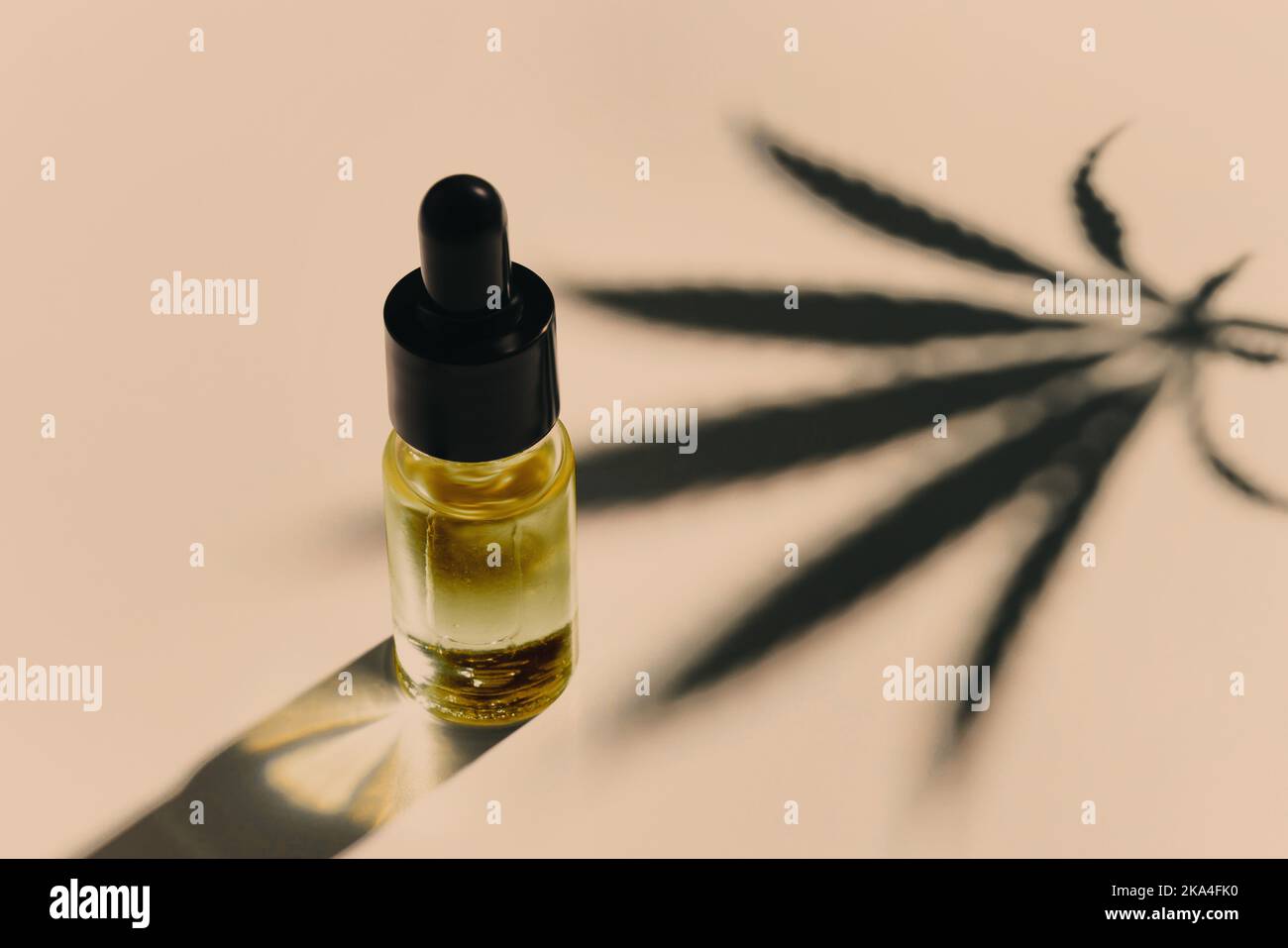 Feuille de chanvre sativa au cannabis avec contenant d'huile de CBD et couvercle compte-gouttes sur fond blanc. Concept de marihuana légalisée. Banque D'Images