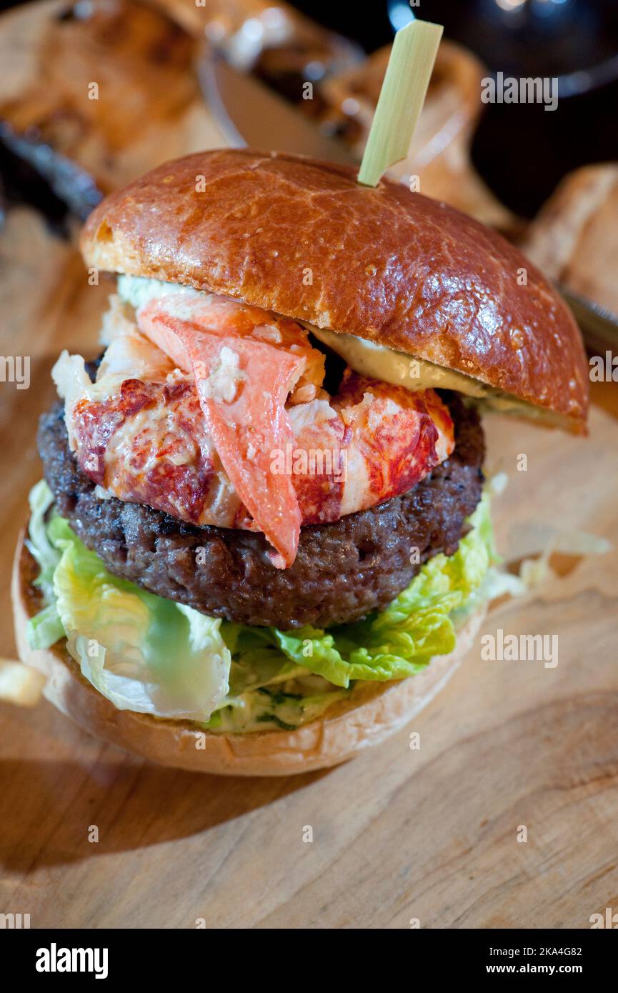 Homard et hamburger de viande servis sur une planche à découper en bois Banque D'Images