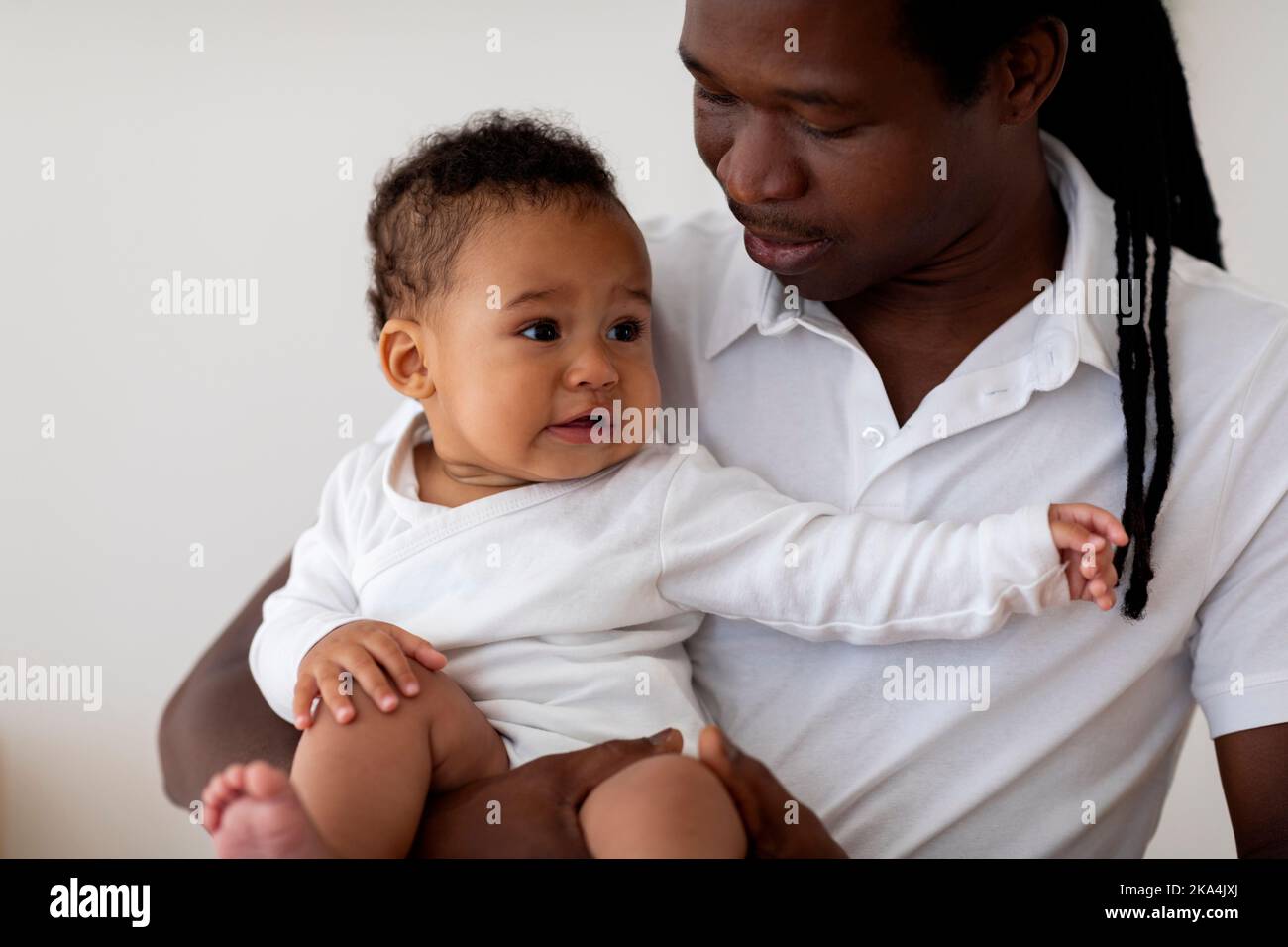 Balançoires d'humeur de bébé. Père noir tenant le bébé en pleurs mignon dans les bras Banque D'Images