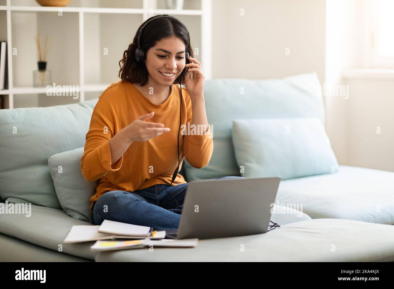 Tutorat en ligne. Femme arabe souriante dans un casque faire une téléconférence avec un ordinateur portable Banque D'Images