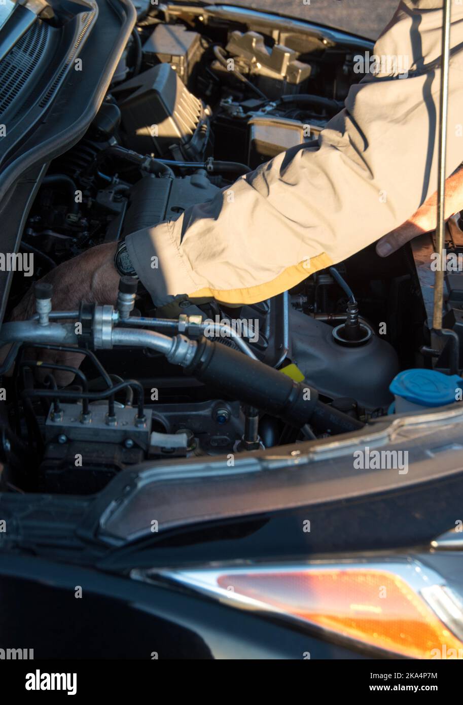 Voiture avec le capot ouvert et une personne, un homme plus âgé, vérifiant ou travaillant sur la voiture. Banque D'Images
