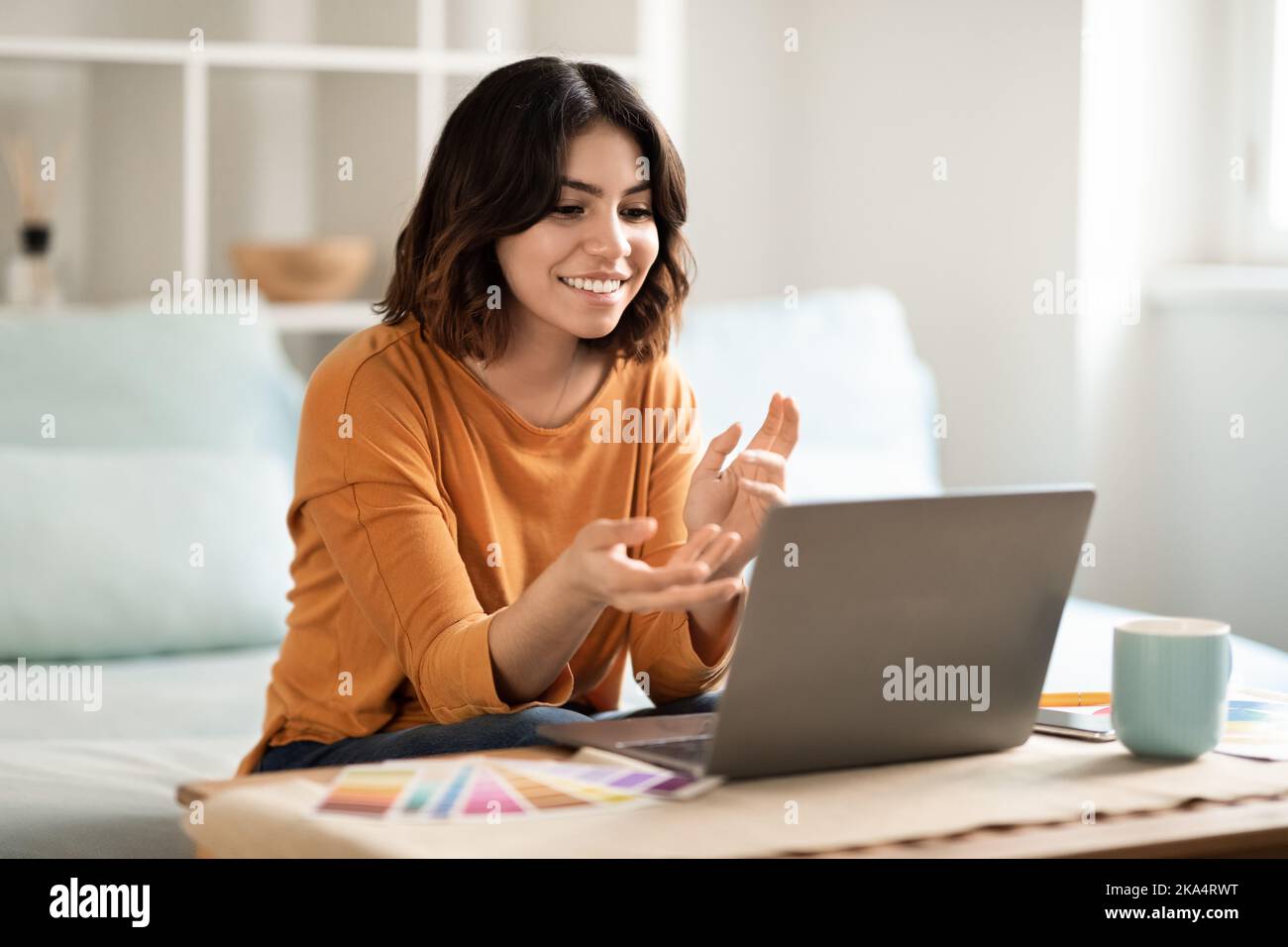Jeune femme de créateur arabe freelance souriante ayant une téléconférence sur ordinateur portable à la maison Banque D'Images