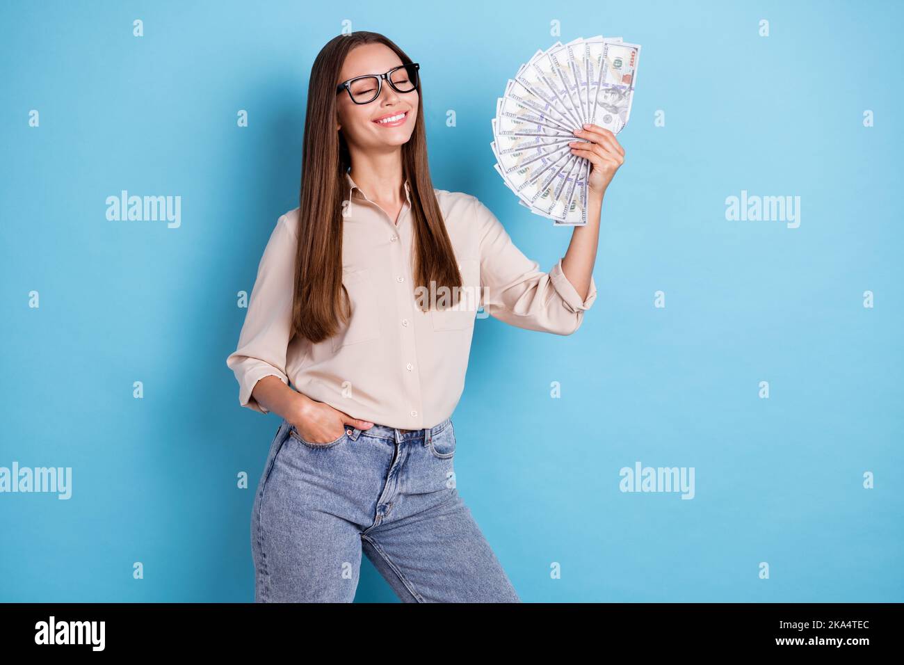 Photo de l'incroyable jolie dame bras tenir grand somme d'argent yeux fermés imaginer shopping isolé sur fond bleu Banque D'Images