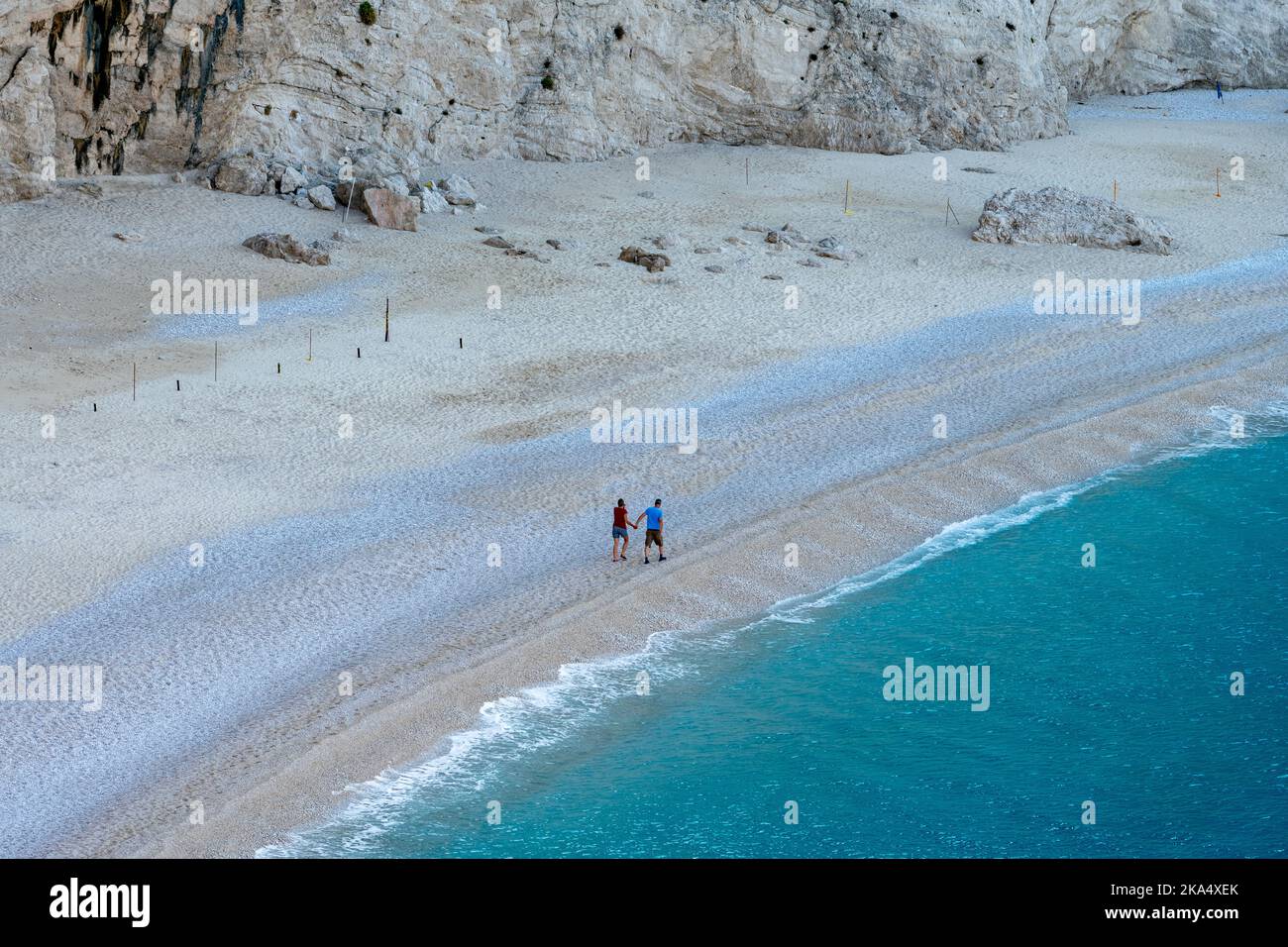 Un couple en vacances marchant sur une belle plage de sable déserte. Banque D'Images