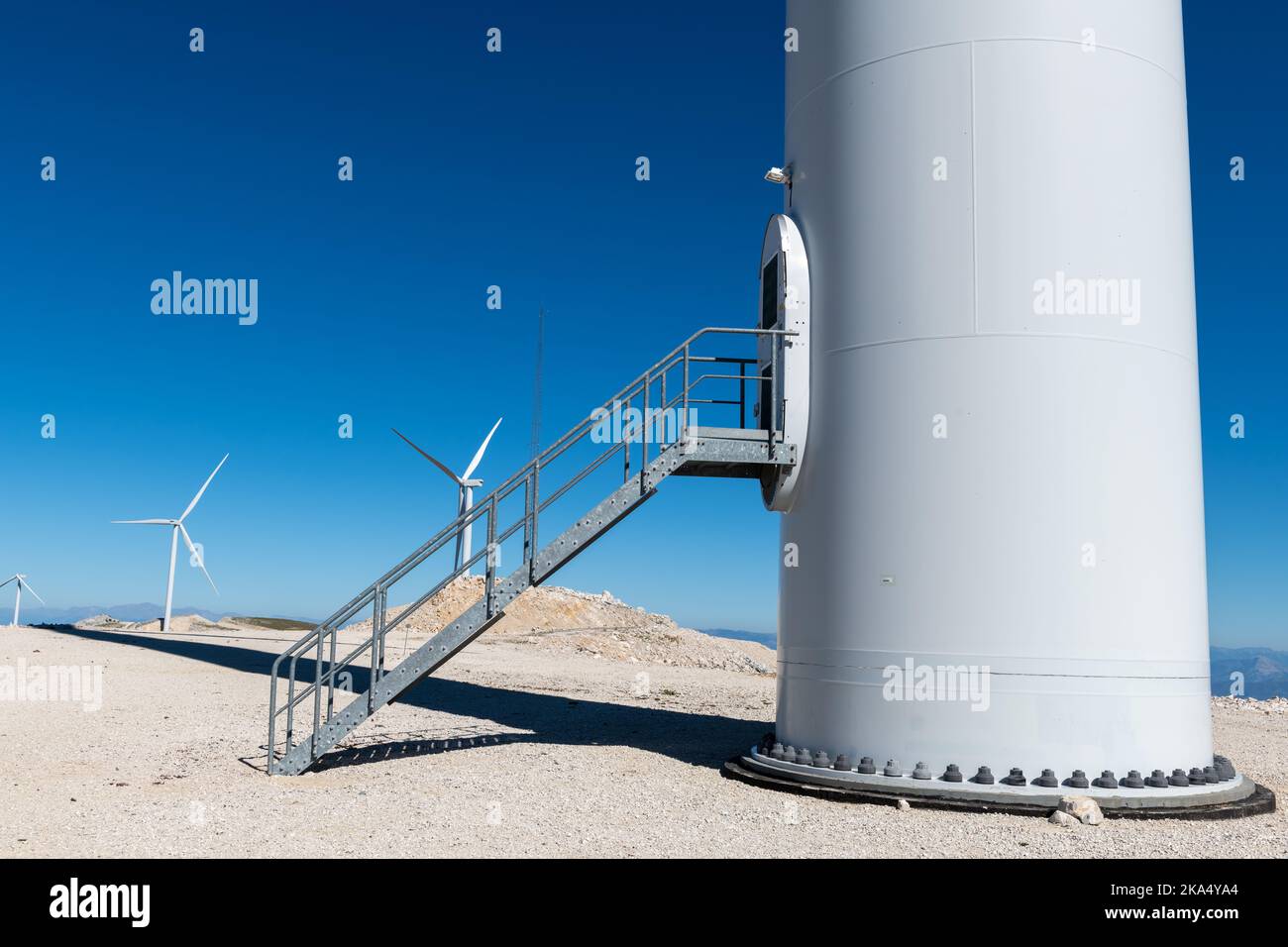 La base d'une éolienne avec un vol d'escaliers et une vue d'autres éoliennes dans le parc éolien. Banque D'Images