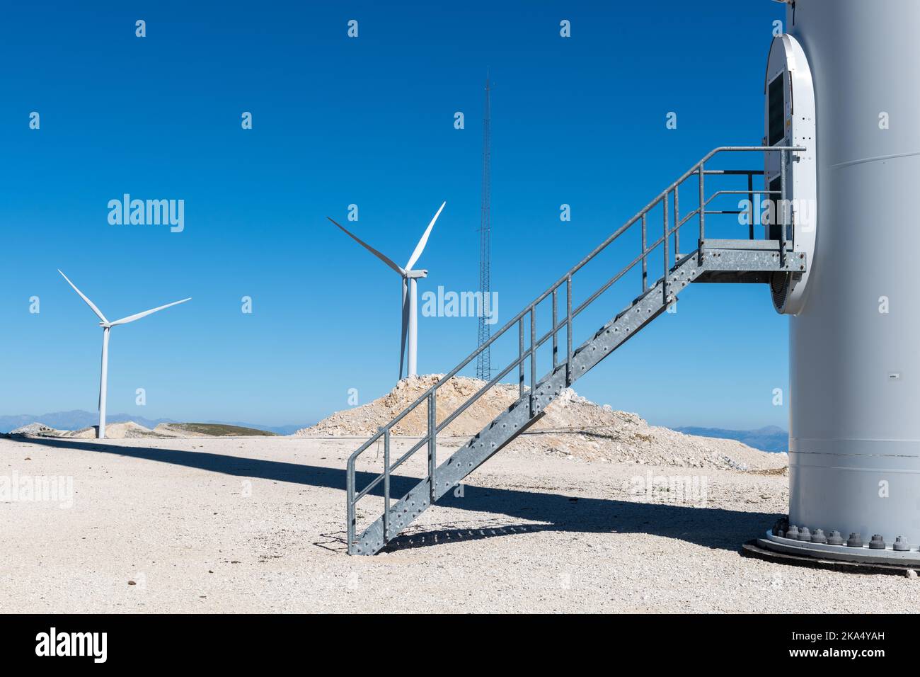 La base d'une éolienne avec un vol d'escaliers et une vue d'autres éoliennes dans le parc éolien. Banque D'Images