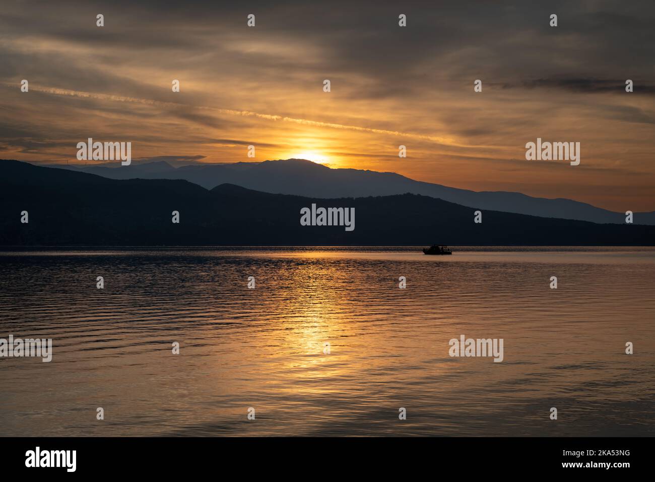 Une petite pêche en mer attrapée dans la lumière réfléchie du soleil se levant sur la colline. Banque D'Images