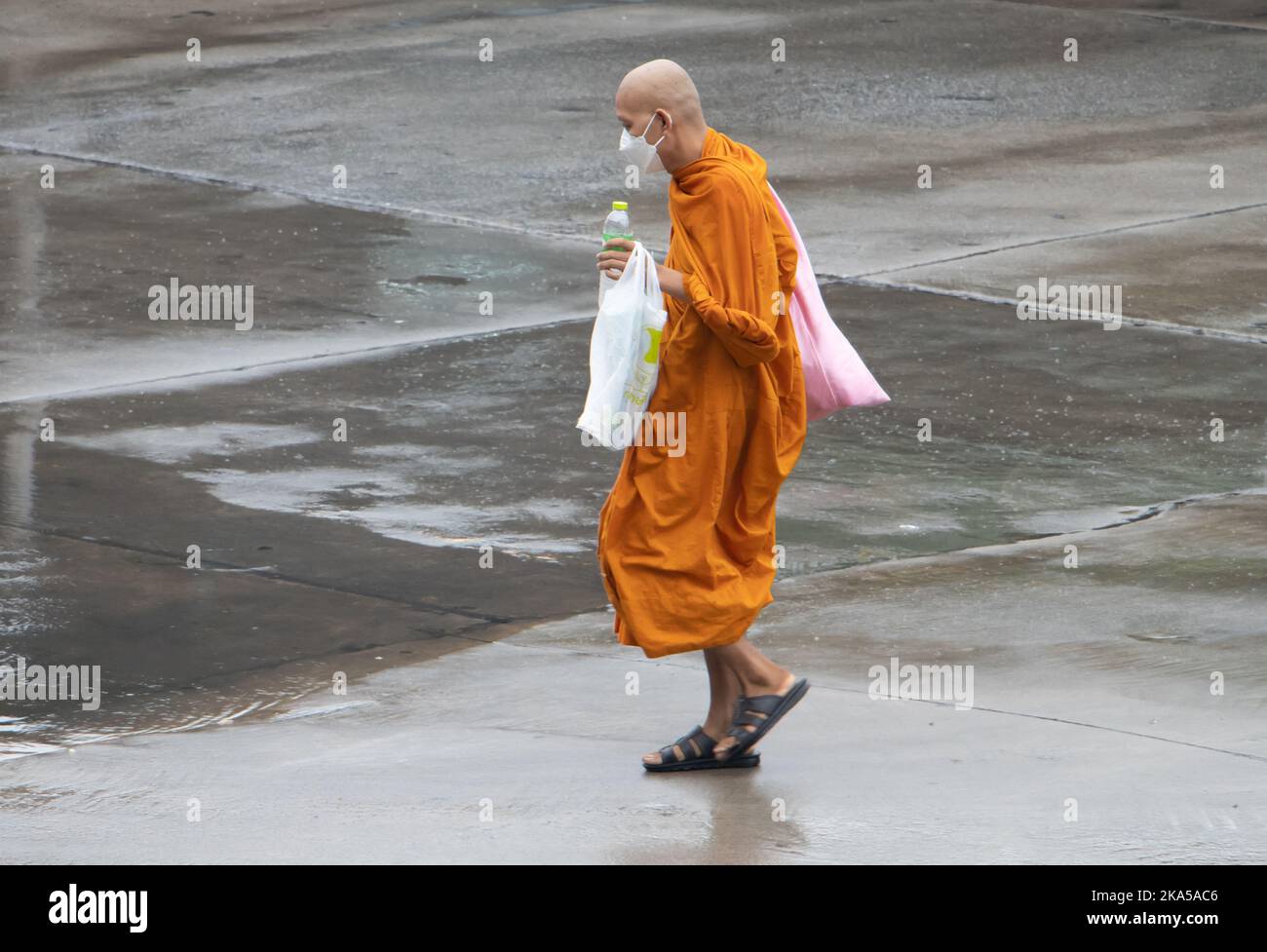 SAMUT PRAKAN, THAÏLANDE, OCT 11 2022, Un moine bouddhiste marche dans une rue humide Banque D'Images