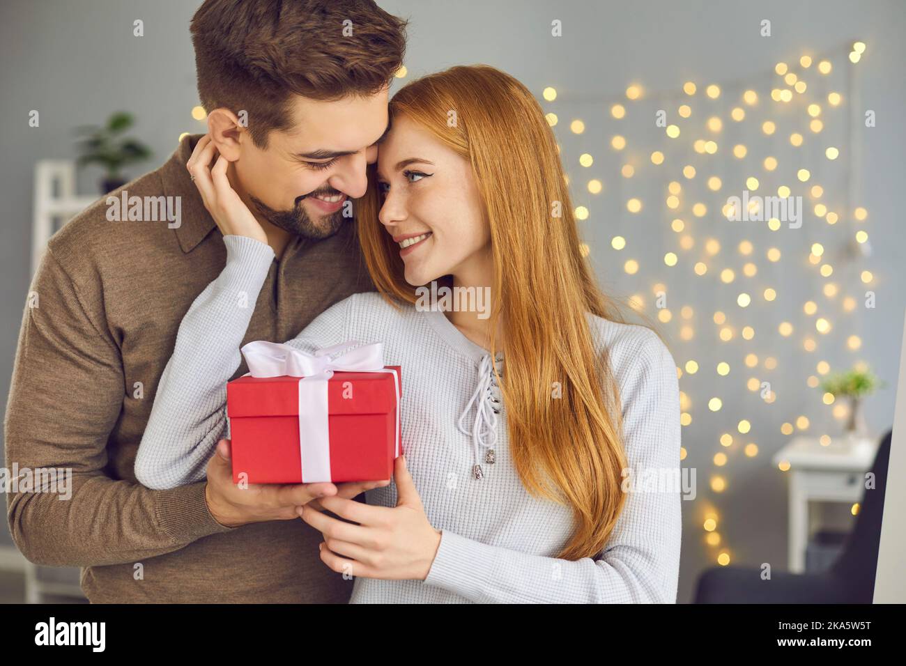 Jeune femme tenant une boîte avec cadeau de Saint-Valentin et remerciant son petit ami pour le cadeau Banque D'Images