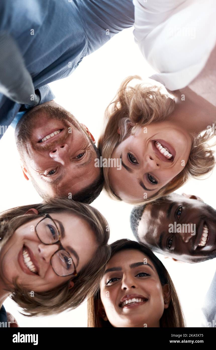 Ensemble. Portrait en bas angle d'un groupe de collègues regardant l'appareil photo tout en étant debout dans un caucus. Banque D'Images