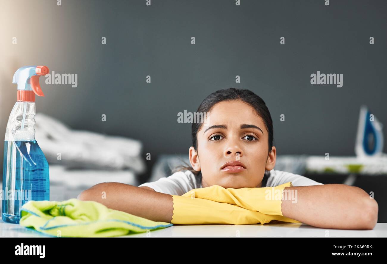 Ennuyé et agité, mais je dois nettoyer. Portrait court d'une jeune femme qui a l'air de s'ennuyer tout en nettoyant une table à la maison. Banque D'Images