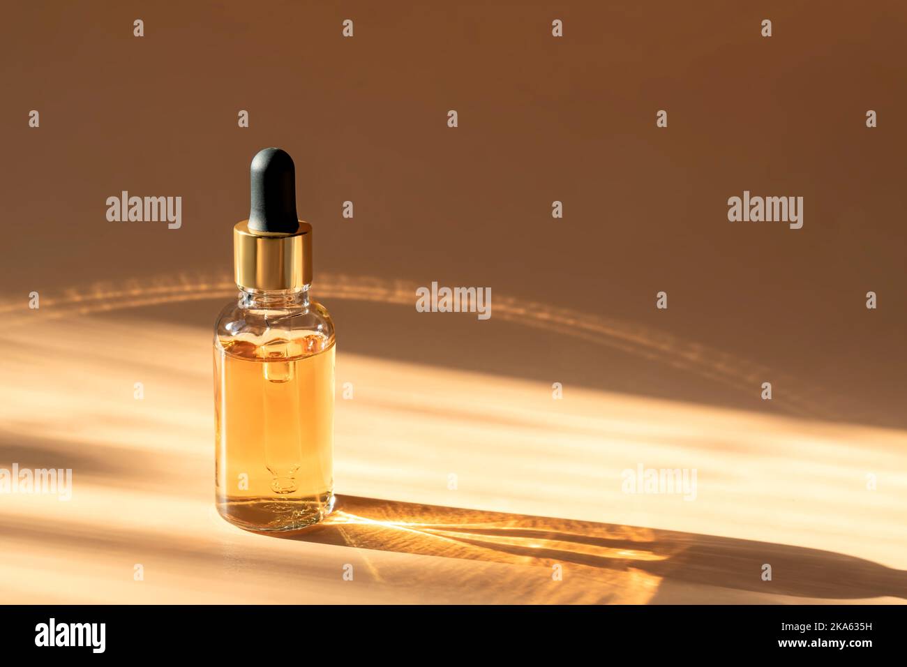 Flacon compte-gouttes en verre Mock-Up. Pipette compte-gouttes avec sérum ou huile essentielle sur fond beige avec ombres caustiques pour la présentation du produit. Soin de la peau c Banque D'Images