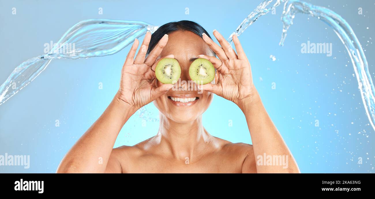 Kiwi fruit, femme et eau de beauté pour les cosmétiques naturels, masque facial et produit de soin sain pour la peau sur fond bleu studio. Bonne face du modèle Banque D'Images