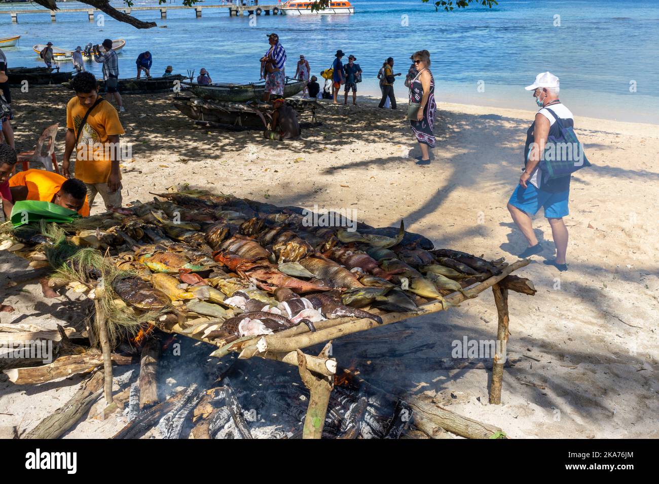 Les locaux préparent et cuisent du poisson au feu ouvert sur la plage, île de Kiriwina, province de Milne Bay, Papouasie-Nouvelle-Guinée Banque D'Images