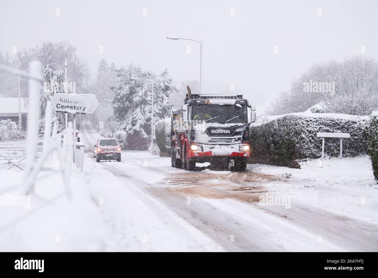 Les gravillons se répandent sur une route enneigée pour aider un camion à grimper une colline glissante, Killéarn, Stirling, Écosse, Royaume-Uni Banque D'Images