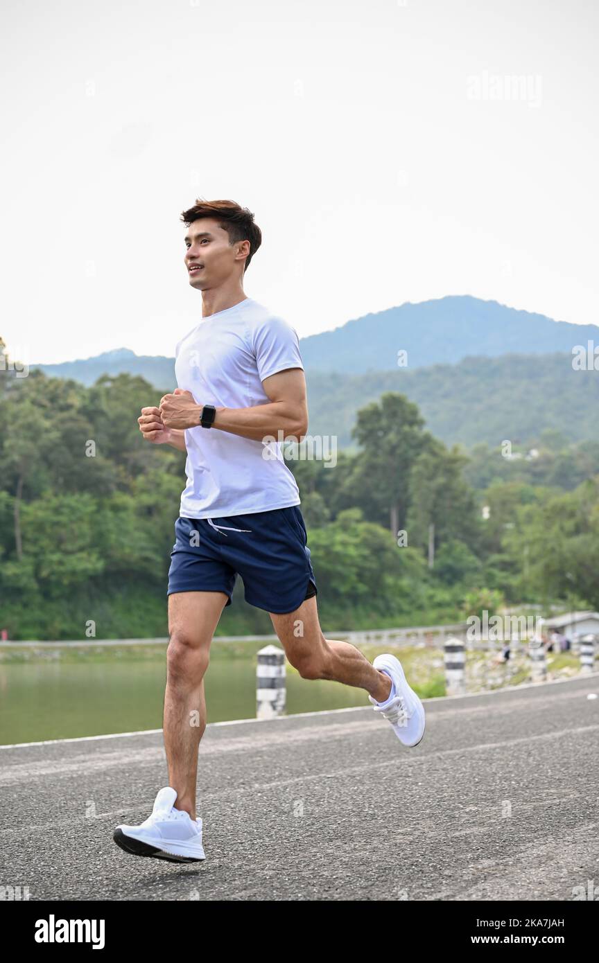 Portrait, belle tenue athlétique jeune homme asiatique dans des vêtements de sport se concentrant sur la course à l'extérieur le matin. Banque D'Images