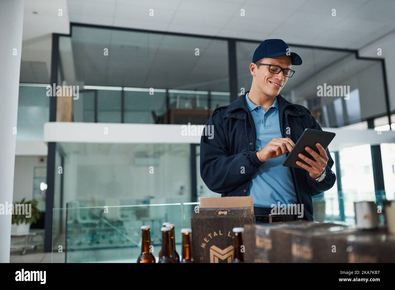 Inventaire sur mon appareil. Un beau jeune homme qui prend l'inventaire des articles qu'il doit livrer aux clients. Banque D'Images