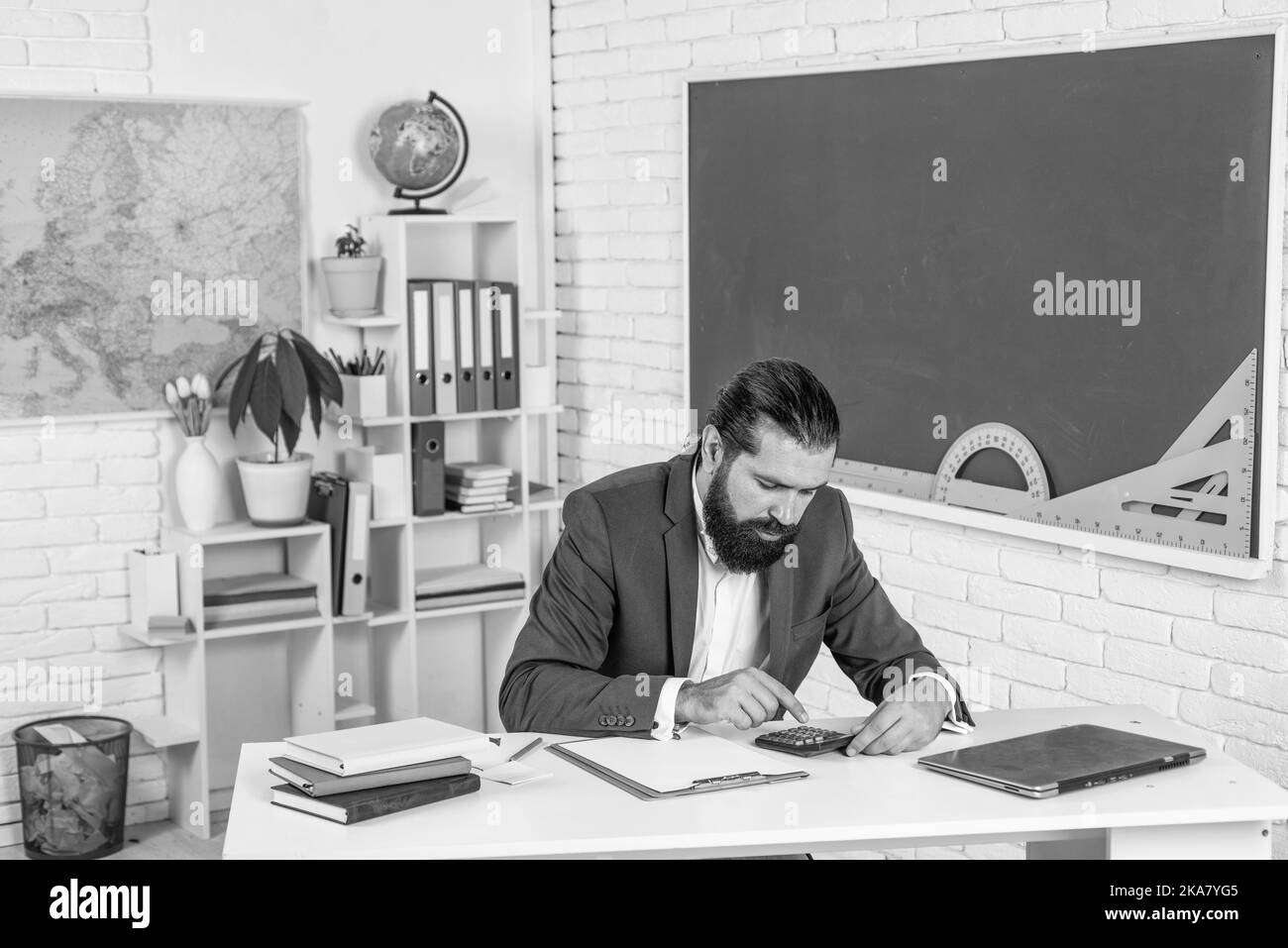 un homme barbu brutal travaille en classe avec une machine à calculer ...