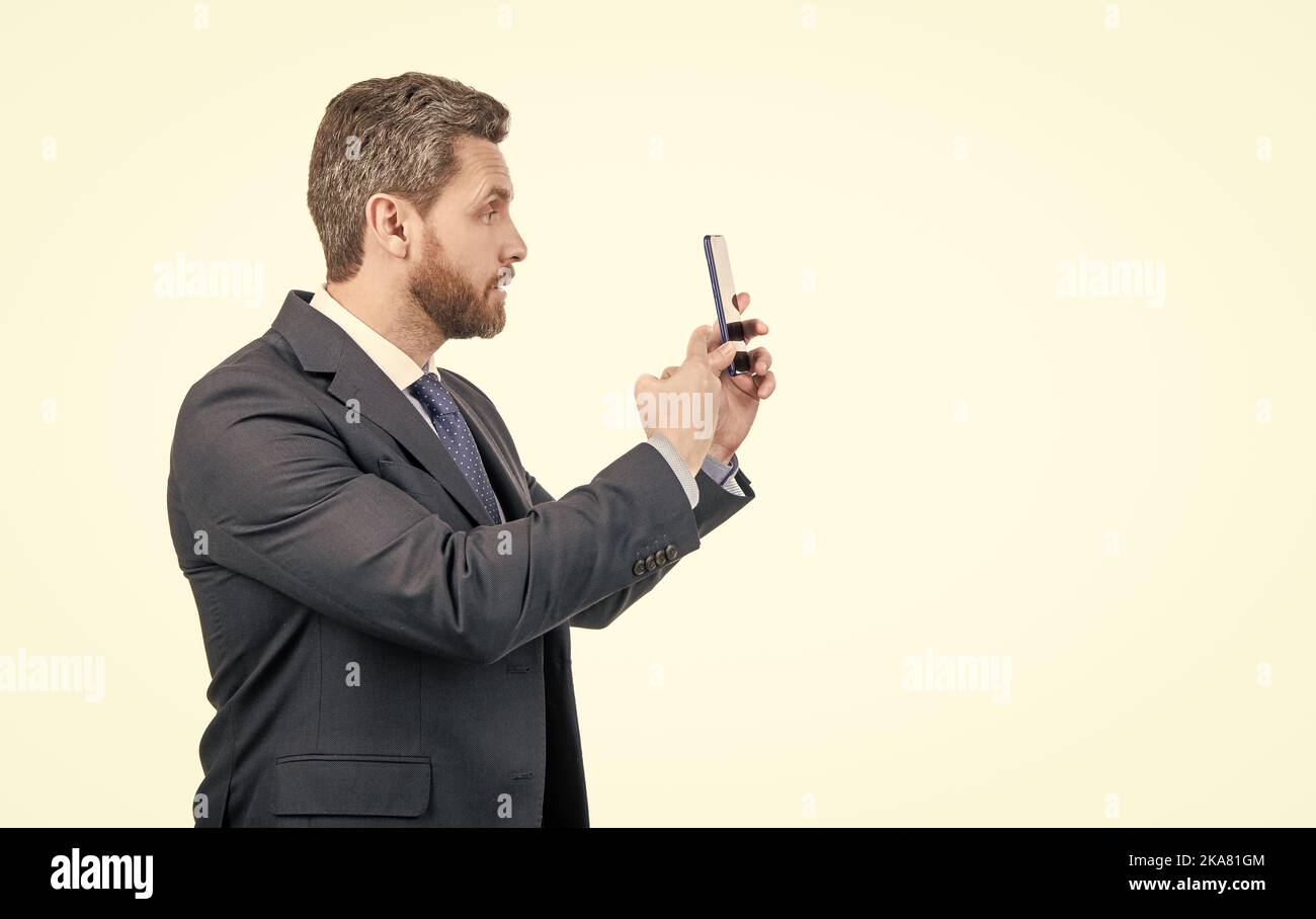 Homme d'affaires en costume de point de doigt sur le téléphone mobile isolé sur l'espace de copie blanc, pointant Banque D'Images