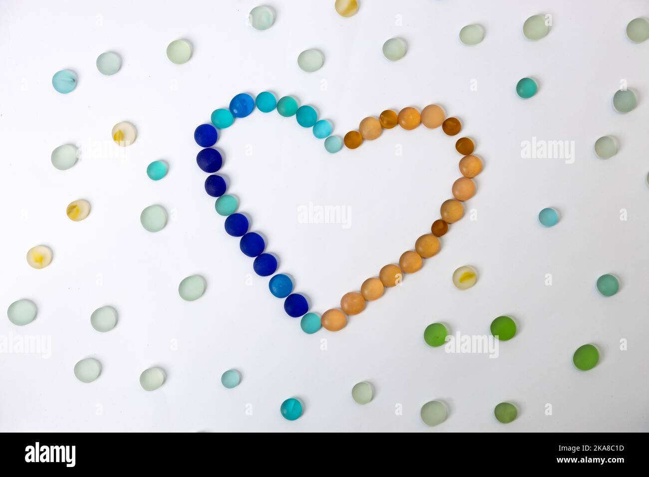 Pierres de verre polies rondes colorées en forme de coeur avec pierres de verre étaler autour sur un arrière-plan isolé. Photo de haute qualité Banque D'Images
