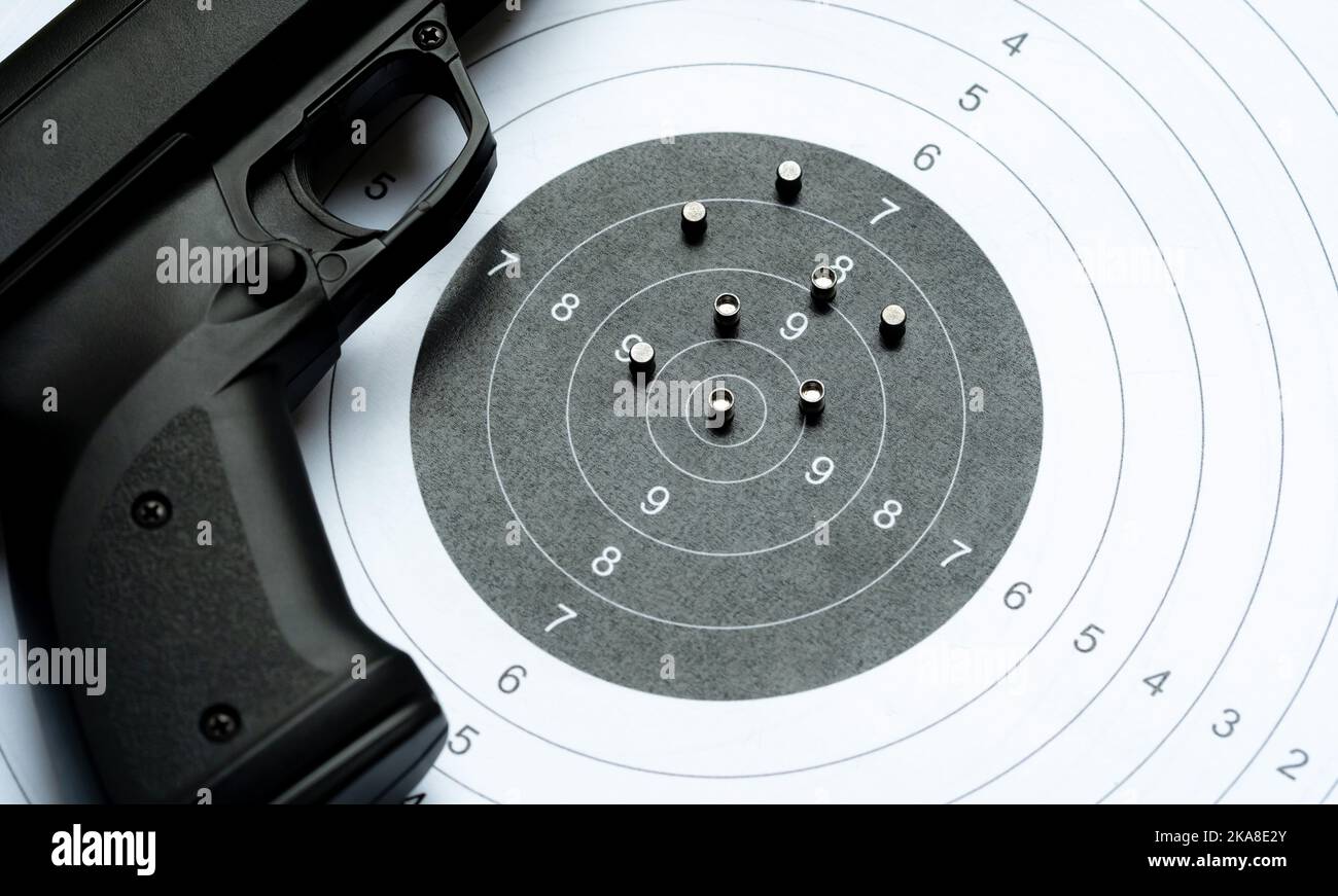 Pistolet à air noir pistolet à pellets posant sur une cible de tir de papier à côté d'un tas de munitions de pellets d'acier. Pistolets à air, sports, concours de tir ai Banque D'Images