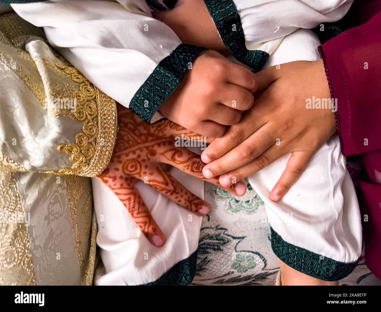 Petite fille avec tatouage de henah tenant la main d'un garçon pendant une cérémonie musulmane Banque D'Images