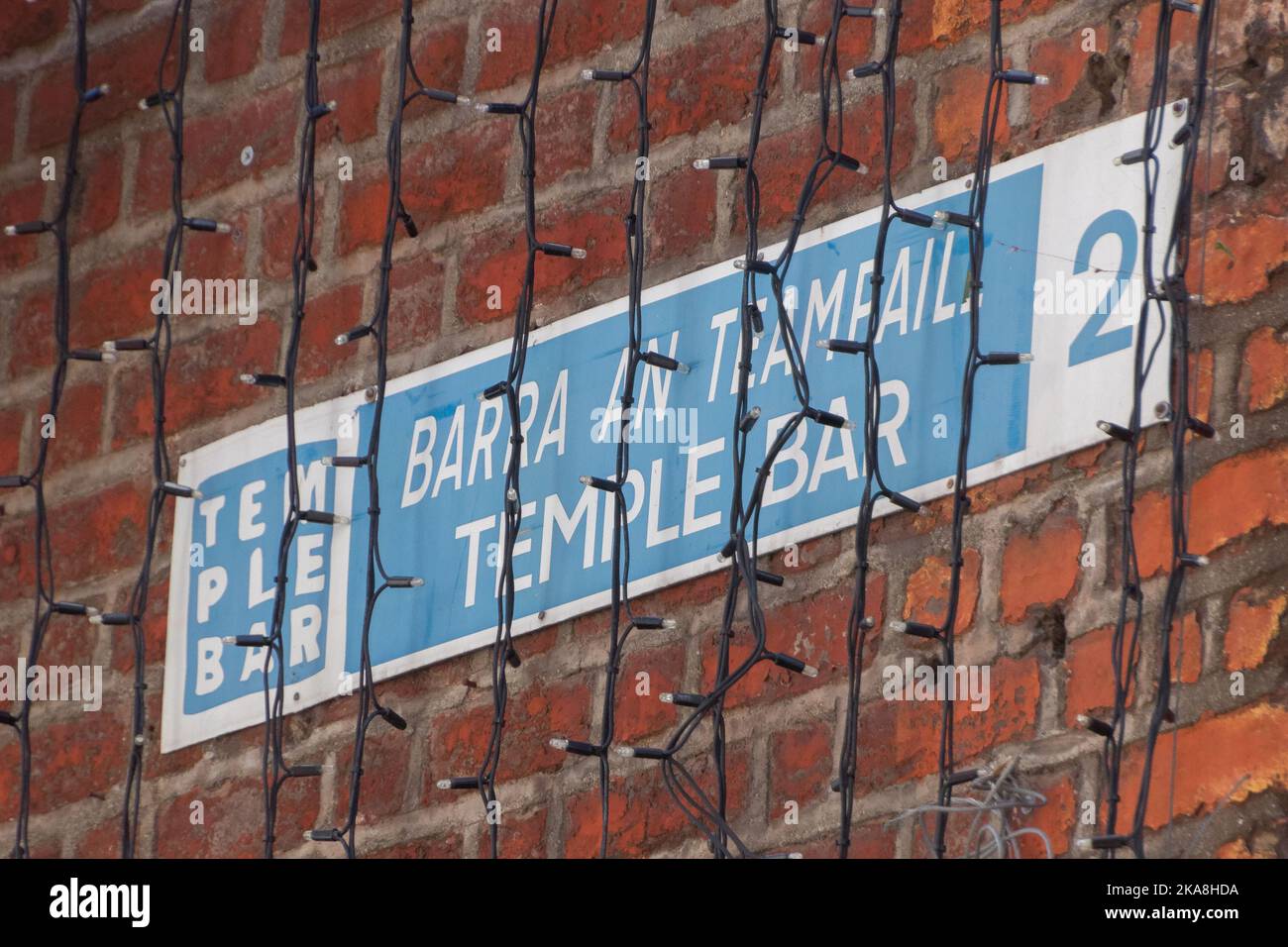 Un gros plan d'un panneau sur un mur de briques avec inscription « Temple bar » derrière des lumières décoratives à Dublin, en Irlande Banque D'Images