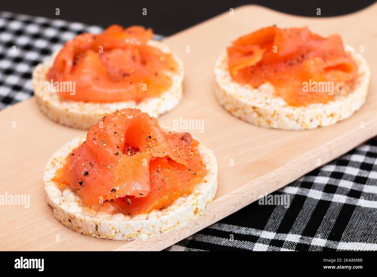 Délicieux sandwichs au gâteau de riz avec tranches de saumon frais sur planche à découper en bois. Petit déjeuner facile et alimentation. Pain croustillant au poisson rouge. En-cas diététiques Banque D'Images