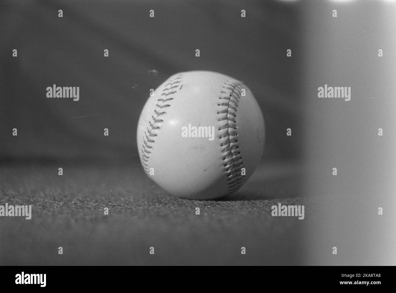 Une photo en niveaux de gris d'une balle de baseball sur une surface plane Banque D'Images