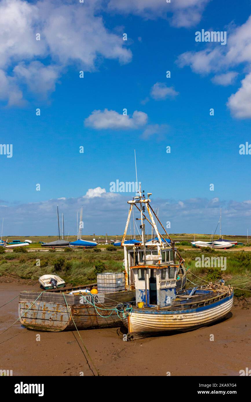 Des bateaux amarrés devant les marais salants plats de Brancaster, sur la côte nord de Norfolk, dans l'est de l'Angleterre britannique. Banque D'Images