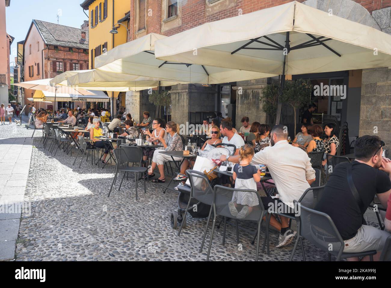 Italie café, vue en été des personnes se détendant dans les terrasses de café situées sur la Piazza San Fedele dans le centre historique de la ville de Côme, Lombardie Banque D'Images