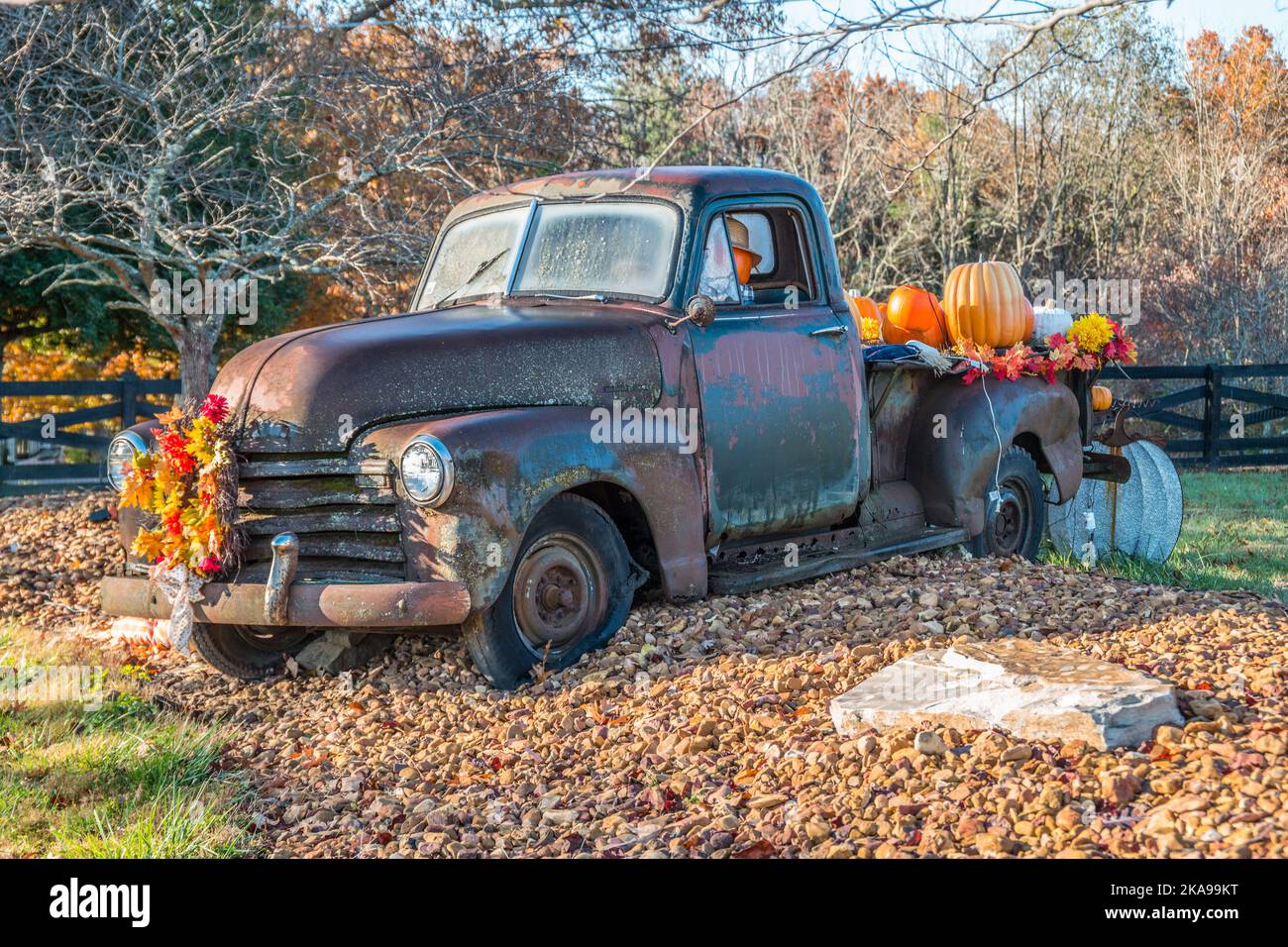 Un vieux camion rouillé d'époque assis à l'extérieur décoré de vacances d'automne avec un homme de citrouille conduisant le camion et d'autres citrouilles dans le dos sur un Banque D'Images