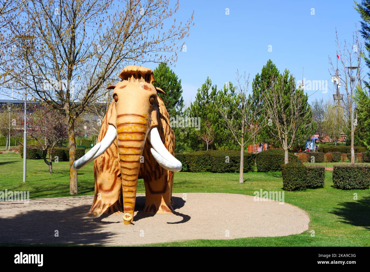 Jouet de mammouth en plastique au parc à l'intérieur de feuilles vertes et d'arbres Banque D'Images