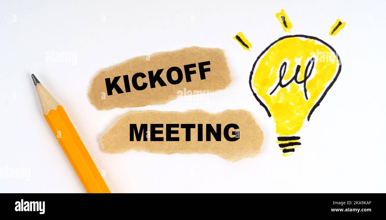 Concept commercial et financier. Une lampe est dessinée sur une feuille blanche, il y a un crayon et des morceaux de papier sur lesquels elle est écrite - Kickoff Meeting Banque D'Images