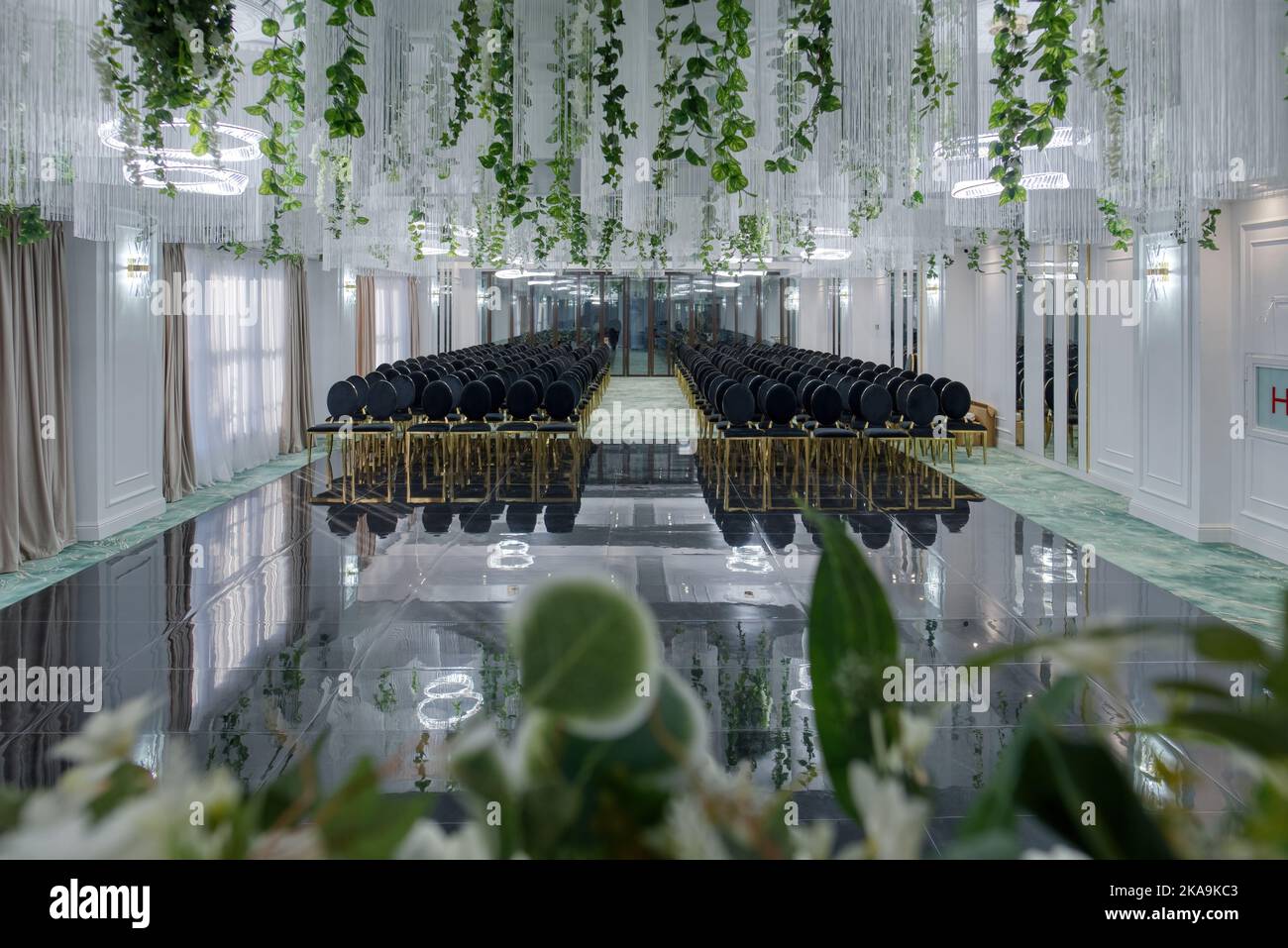 Salle de conférence de l'hôtel avec chaises vides, design vert avec plantes vertes et fleurs. Banque D'Images