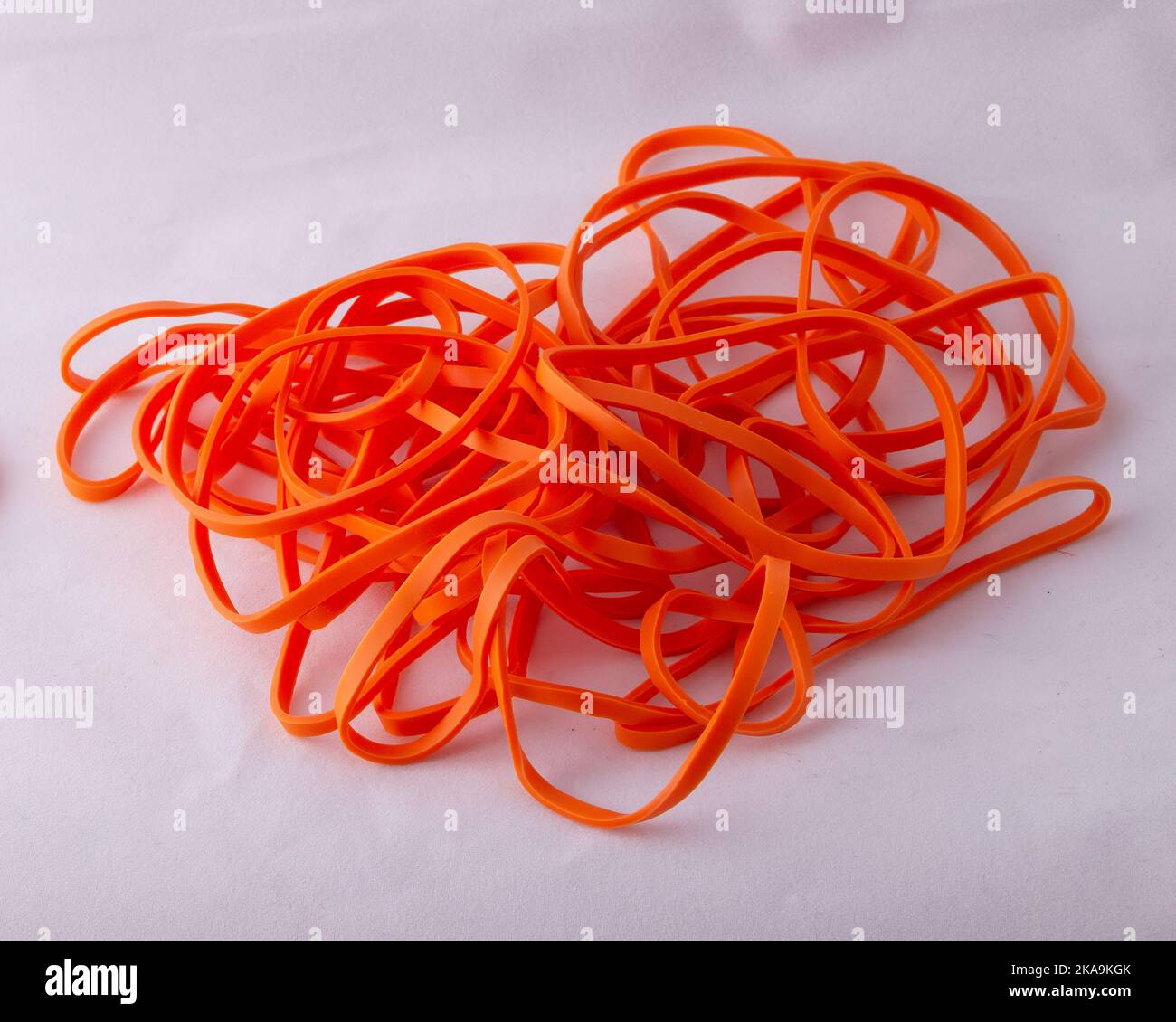 Pile de bandes de caoutchouc orange néon isolées sur fond blanc Banque D'Images