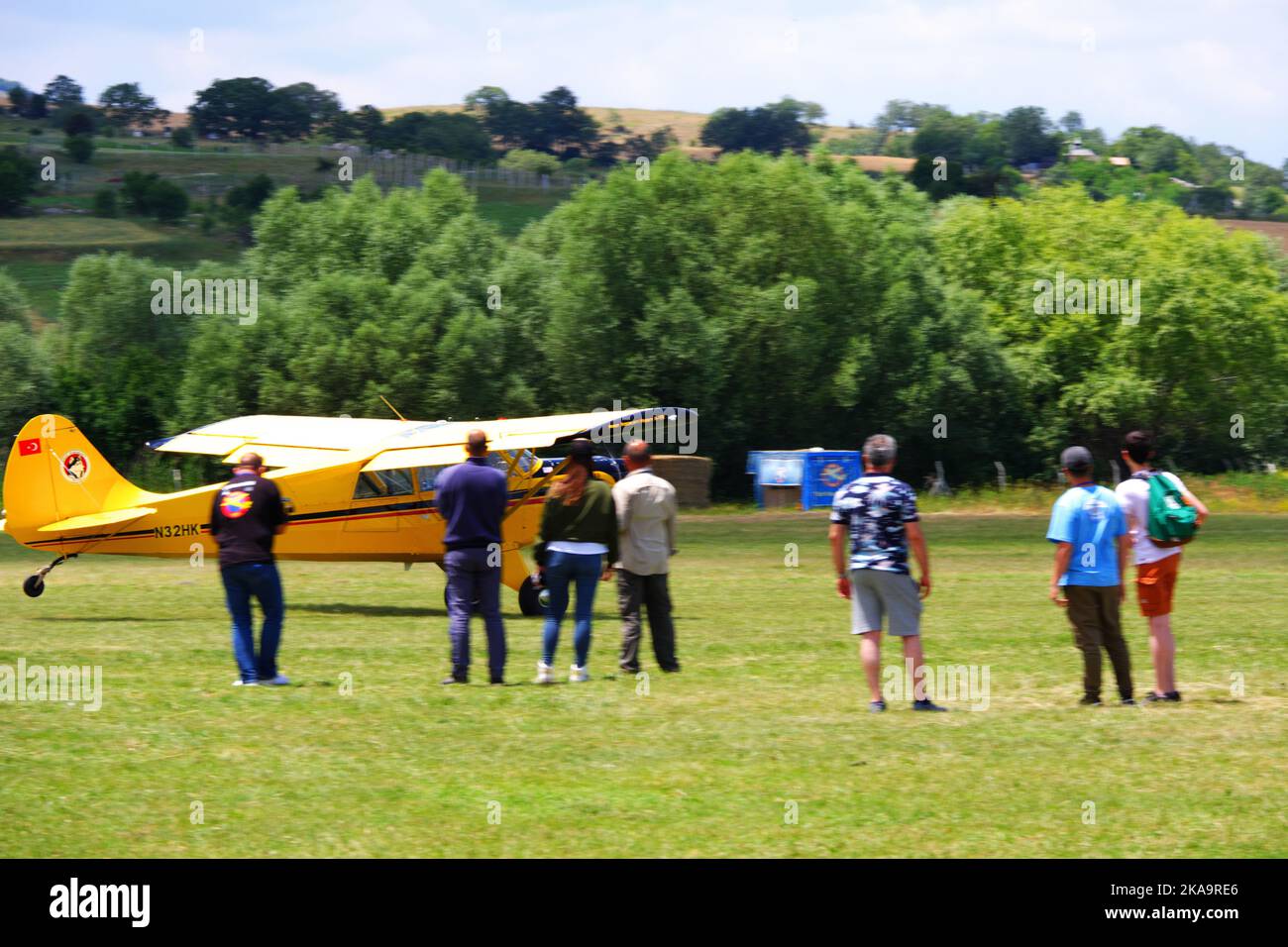 Avion jaune garé sur l'herbe avec des personnes autour de lui sur l'herbe dans une journée ensoleillée à l'extérieur Banque D'Images