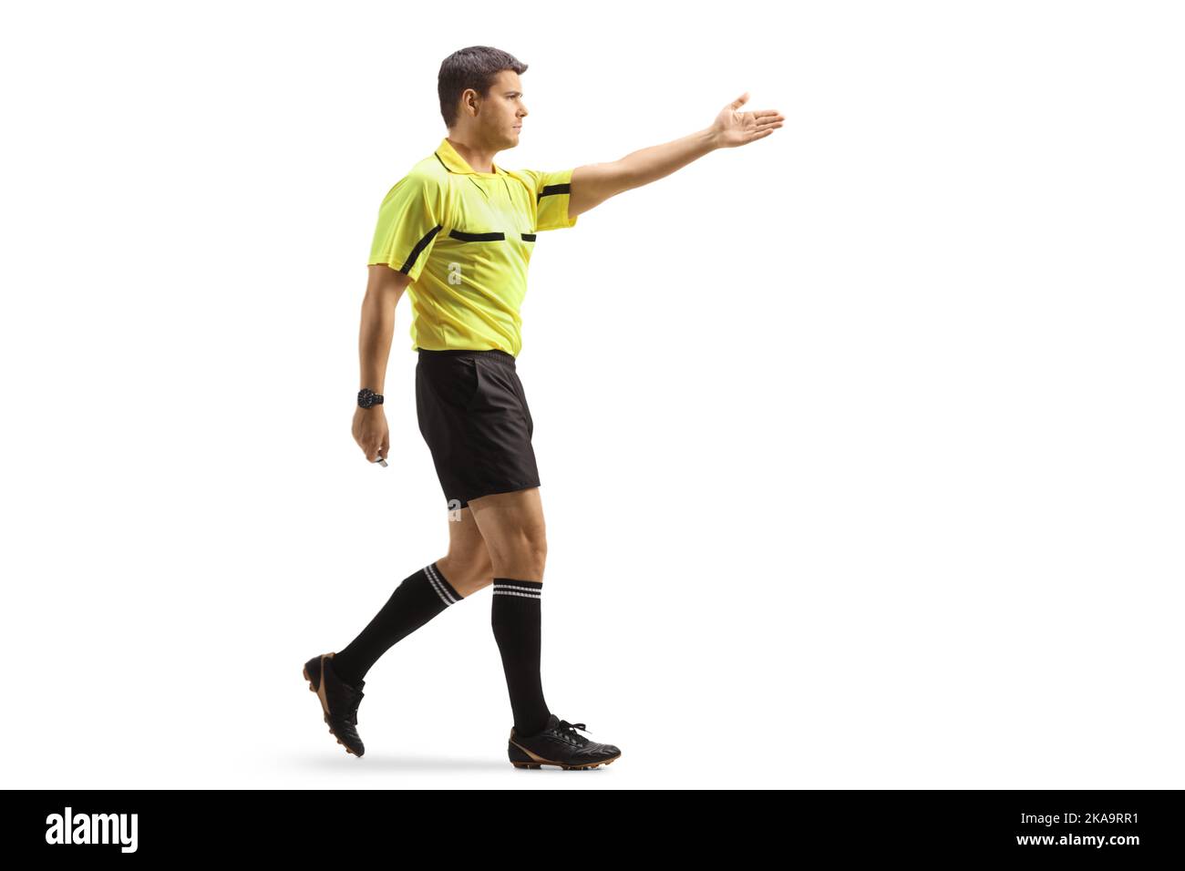 Prise de vue sur toute la longueur d'un arbitre de football pointant avec la main et la marche isolée sur fond blanc Banque D'Images