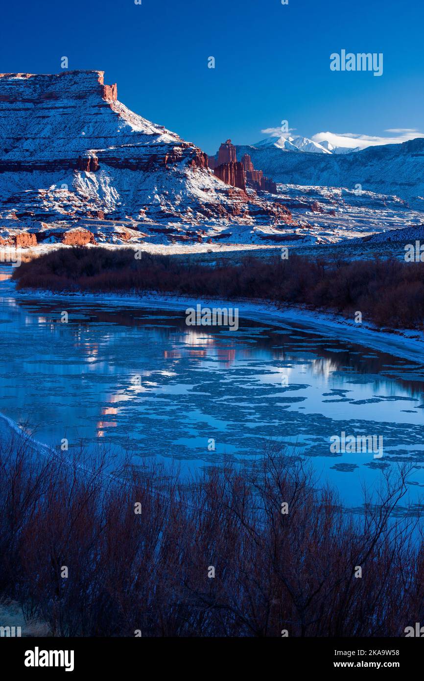 Fisher Towers au-dessus du fleuve Colorado glacé au coucher du soleil en hiver avec les montagnes de la Sal derrière. Près de Moab, Utah. Banque D'Images